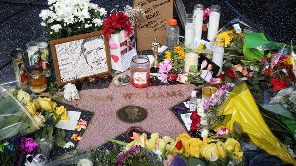 Flowers, photographs and candles surround the star of actor-comedian Robin Williams forming a makeshift memorial along the Hollywood Walk of Fame in Los Angeles on Tuesday, Aug. 12, 2014. Williams, 63, died at his San Francisco Bay Area home Monday in an 