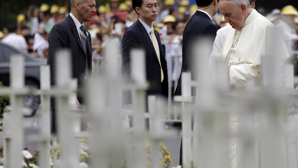 Pope Francis prays in front of white wooden crosses of the unborn children garden during his visit to the 