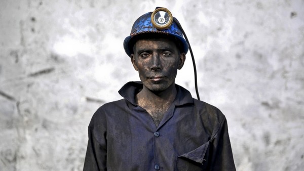 In this Wednesday, May 7, 2014 photo, an Iranian coal miner with his face smeared black from coal poses for a photograph at a mine near the city of Zirab 212 kilometers (132 miles) northeast of the capital Tehran, on a mountain in Mazandaran province, Ira