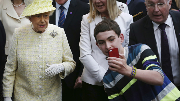 FOR USE AS DESIRED, YEAR END PHOTOS - FILE - A local youth takes a selfie photograph in front of Queen Elizabeth II during a visit to St George's indoor market on in Belfast Tuesday June 24, 2014. The Queen is on a 3 day visit to Northern Ireland. (AP Pho