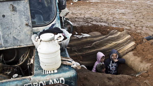 In this Saturday, Nov. 22, 2014 photo, children stand in a trench built for mortar attacks by Islamic State group fighters against the civilians in the buffer zone near the Turkish border in Kobani, Syria. Here, Kurdish fighters backed by small numbers of