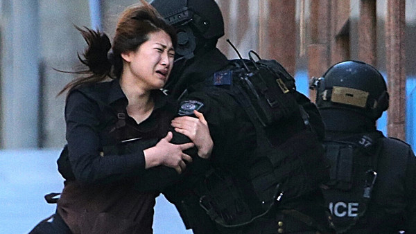 A hostage runs to an armed tactical response police officers for safety after she escaped from a cafe under siege at Martin Place in the central business district of Sydney, Australia, Monday, Dec. 15, 2014. (AP Photo/Rob Griffith)
