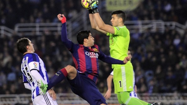 Barcelona's Luis Suarez of Uruguay, center, jumps for the ball in front Real Sociedad's goalkeeper Geronimo Rulli of Argentina, during their La Liga soccer match, at Anoeta stadium in San Sebastian, northern Spain, Sunday, Jan. 4, 2015. (AP Photo/