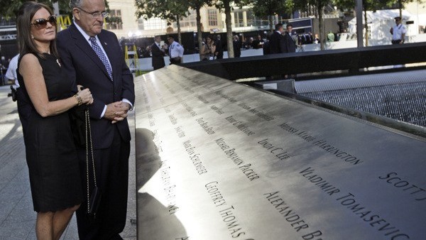 Former New York City Mayor Rudy Giuliani and his wife Judith Nathan pay their respects at the north reflection pool near the bronze-etched names of the victims of the 9/11 terrorist attack on the National September 11 Memorial during a ceremony marking th