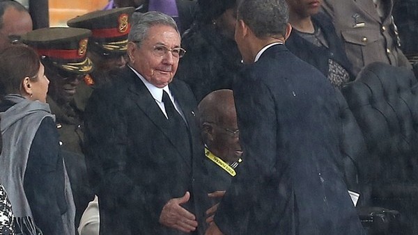 US President Barack Obama shakes hands with Cuban President Raul Castro at the FNB Stadium in Soweto, South Africa, in the rain for a memorial service for former South African President Nelson Mandela, Tuesday Dec. 10, 2013. The handshake between the lead