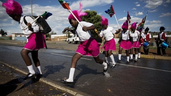 Drum majorettes negotiate their way through water flowing down a street en route to Vilakazi Street in the Soweto township, Johannesburg, South Africa, Sunday, Dec. 15, 2013. Anti-apartheid champion Nelson Mandela was buried in his home village on Sunday 