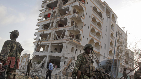 An African Union (AU) soldier walks past the scene of destruction following a suicide car bomb attack in the capital Mogadishu, Somalia Sunday, July 26, 2015. A Somali police officer says a suicide car bomber has rammed his car into the protective perimet