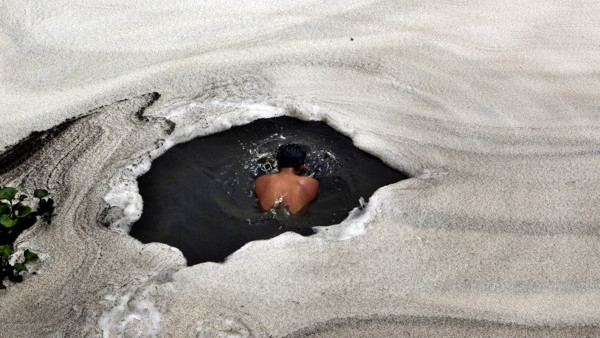 An Indian boy takes a dip in the River Yamuna with froth from industrial pollution floating on the surface, in New Delhi, India, Saturday, June 5, 2010. World Environment Day 2010 being marked Saturday calls for an urgent need to conserve the diversity of
